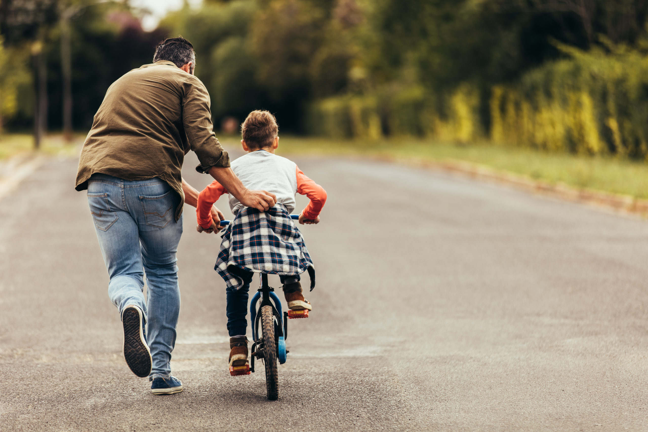 Man helping son ride bike, Child Support Myths