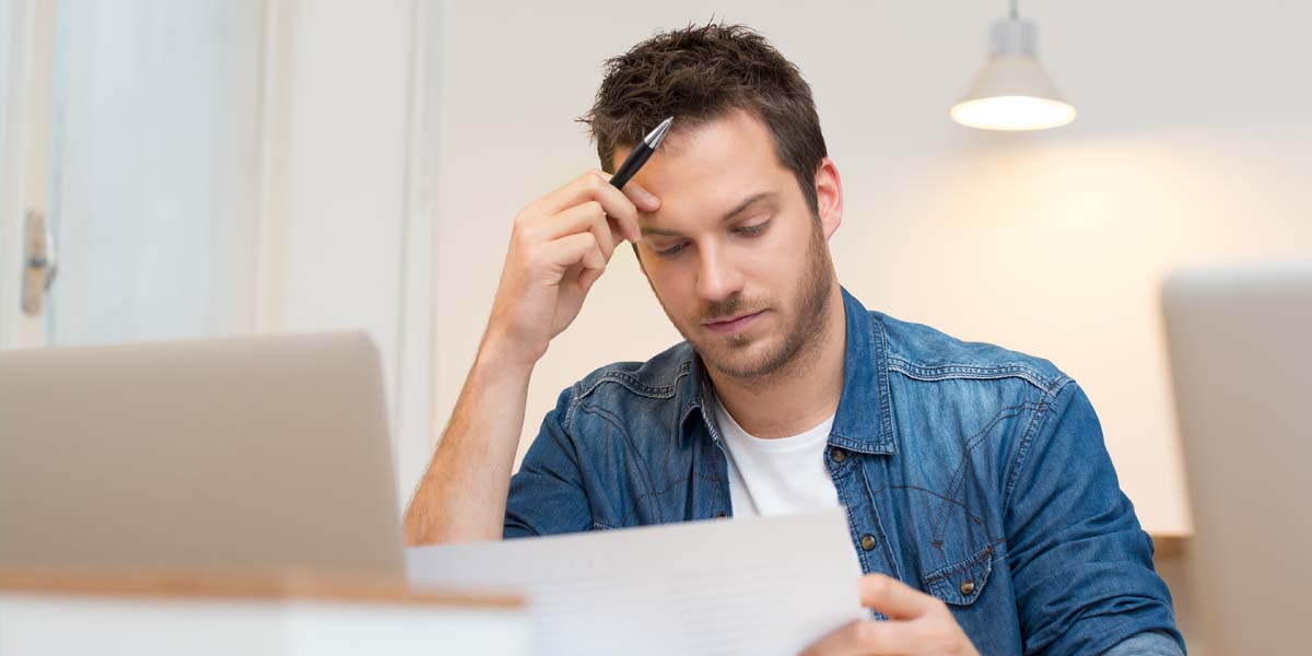 Man in blue shirt doing paperwork, dealing with stress of representing yourself.