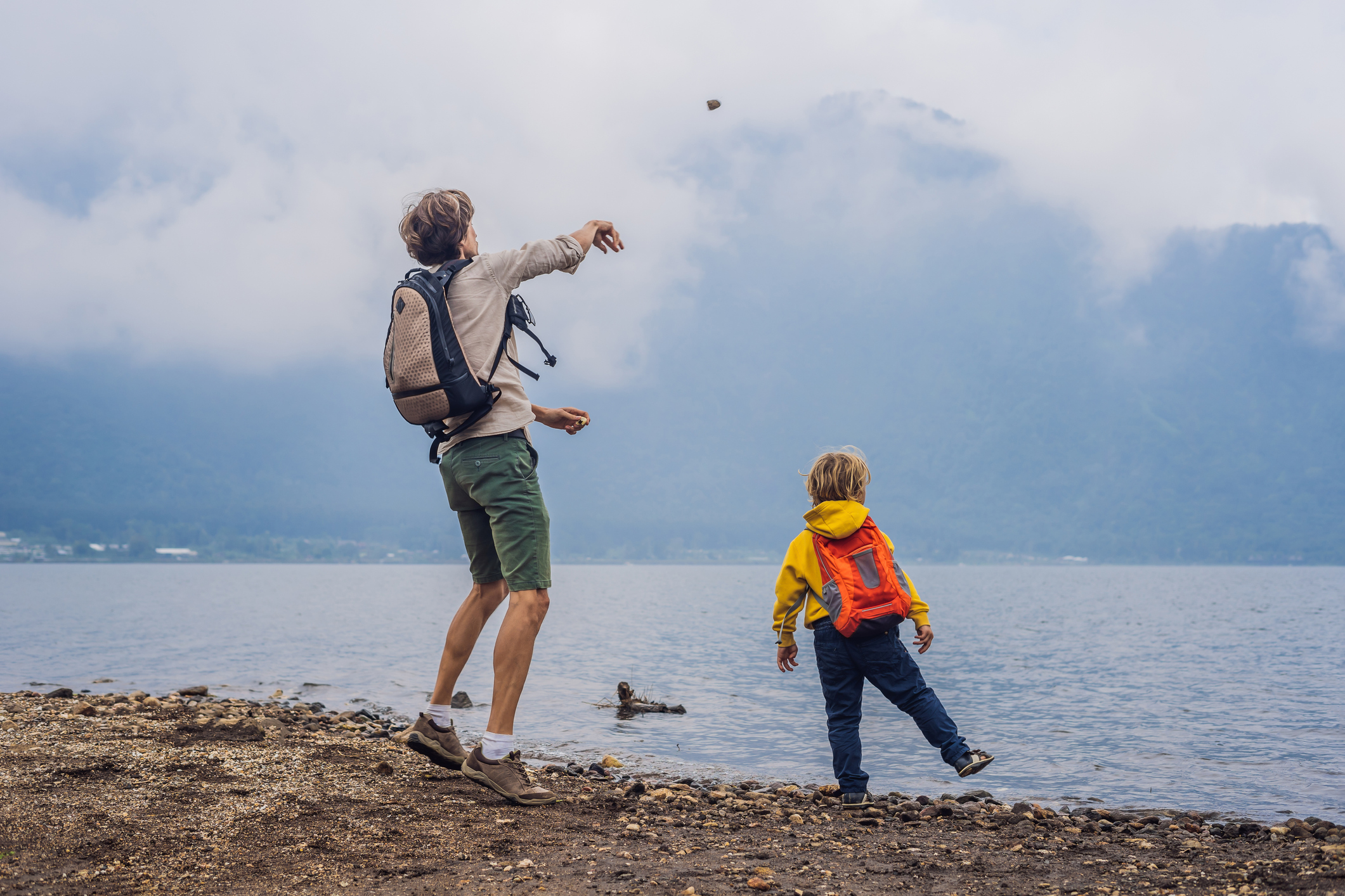 how to deal with summer visitation: father and son throwing rocks into lake